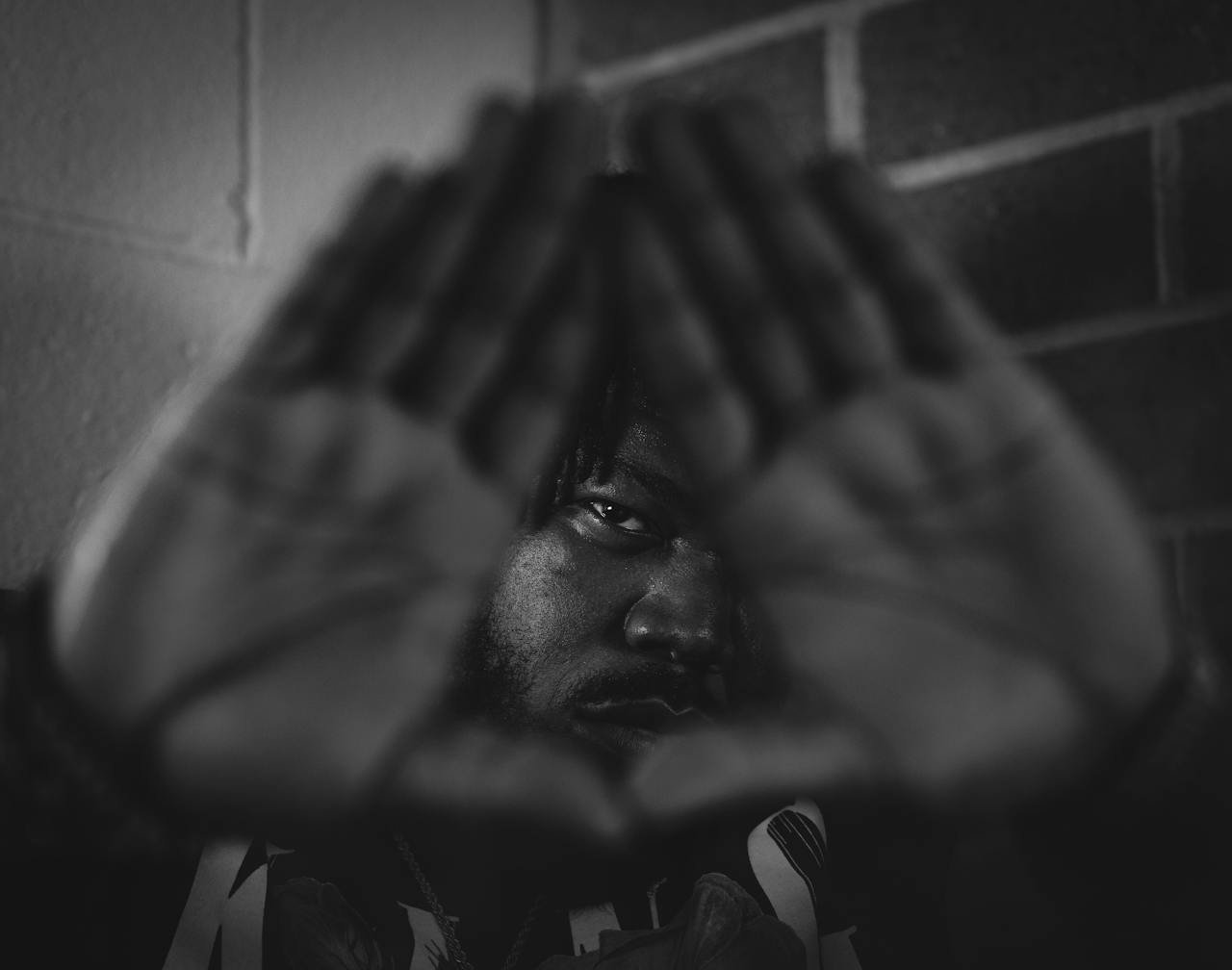 Black and white portrait conveying emotion through triangle hand gesture.